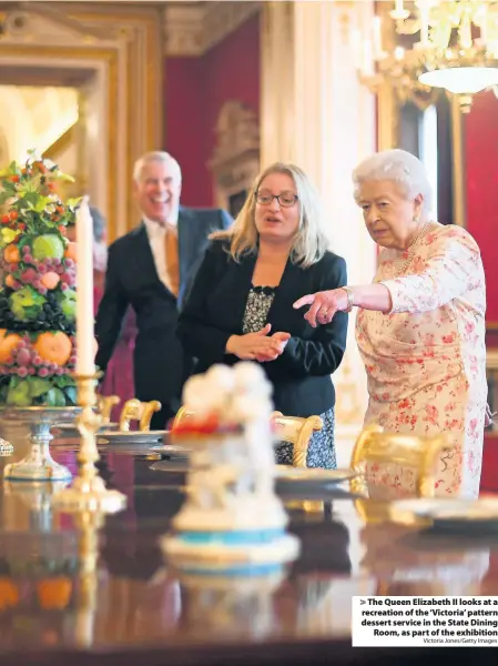  ?? Victoria Jones/Getty Images ?? The Queen Elizabeth II looks at a recreation of the ‘Victoria’ pattern dessert service in the State Dining
Room, as part of the exhibition