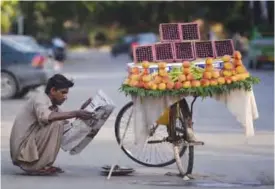  ??  ?? ISLAMABAD: A Pakistani fruit vendor reads a newspaper as he waits for customers on a street in Islamabad yesterday. — AFP