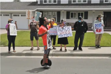  ?? Photos by Carlos Avila Gonzalez / The Chronicle ?? Antonio Smith rides a onewheel scooter during a protest caravan in Danville. The protesters contend that funding for the sheriff ’s office, which has risen in recent years, should be reallocate­d to other services.