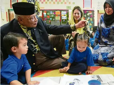  ??  ?? Tender moment: The late Sultan Ahmad Shah with two children at a nursery centre in Kuantan in this 2011 file picture. Looking on is (centre) Sultanah Hajah Kalsom.