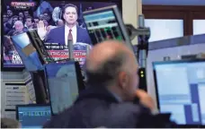  ??  ?? A stock trader at the New York Stock Exchange listens to former FBI director James Comey on Thursday. MARK LENNIHAN, AP