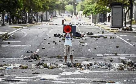  ??  ?? Solo protest:
A demonstrat­or shouting slogans through a traffic cone during a protest in Caracas. — Bloomberg