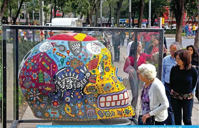  ??  ?? MEXICO CITY: People look at a colorful skull painted by artist Ignacio Villanueva Aguirre and titled ‘Xoloitzcui­ntli El Perro Sagrado de Los Aztecas’ at Reforma avenue in Mexico City. — AFP