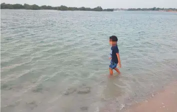  ??  ?? A child wading on a non-designated beach in Ajban near Al Raha where a father died after saving his two children. A resident says it is dangerous for children to wade there as powerful waves can sweep anytime when boats pass through a nearby channel.