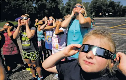  ?? CHARLIE RIEDEL/THE ASSOCIATED PRESS ?? Fourth-graders at Clardy Elementary School in Kansas City, Mo. practice the proper use of their eclipse glasses Thursday in anticipati­on of Monday’s solar eclipse. Schools around the country preparing for the solar eclipse are reacting in a variety...