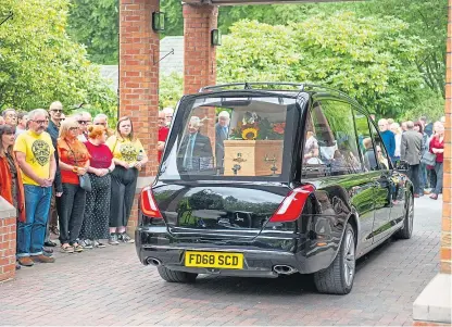  ?? Pictures: Kim Cessford. ?? Brightly dressed mourners watch as the hearse arrives at the crematoriu­m.