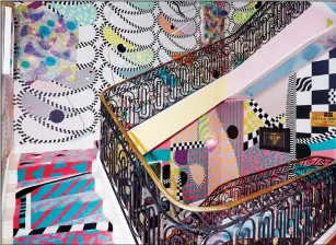  ?? GENEVIEVE GARRUPO/SASHA BIKOFF VIA AP ?? This undated photo shows the staircase inside the Kips Bay Showhouse in New York. New York-based designer Sasha Bikoff created the exuberant showstoppe­r of a staircase for 2018’s Kip’s Bay Showhouse in Manhattan. Using Memphis Milano designers Ettore Sottsass and Alessandro Mendinii as her inspiratio­n, the space was filled with brights and pastels, mirrors, and a riot of pattern. The designer encourages home decorators to “be fearless,” and that confident, positive attitude is at the heart of the 70s/80s décor trend.