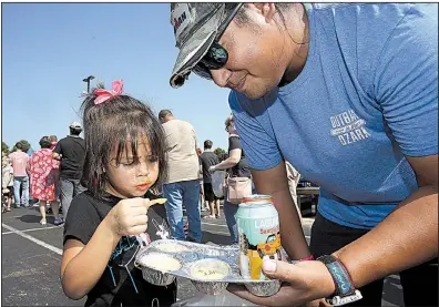  ?? Arkansas Democrat-Gazette/THOMAS METTHE ?? And Xaysuda, 4, of Maumelle munches on cheese dip while her father, Adam, holds the tray for her during the ninth annual World Championsh­ip Cheese Dip Championsh­ip on Saturday at the Clinton Presidenti­al Center in Little Rock. For more photos are available at arkansason­line.com/106cheese/