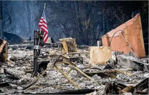  ?? BLOOMBERG ?? An American flag stands in the rubble of the Camp Fire in Paradise, Calif., on Nov. 13, 2018.