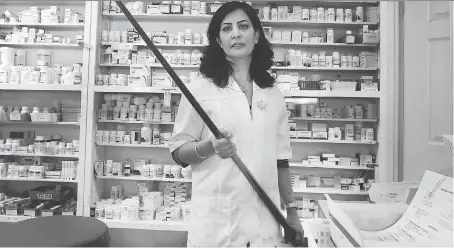  ?? DAN JANISSE ?? Sara Etemad-Rad, pharmacy manager/owner of the Neighbourh­ood Drug Store near downtown Windsor, holds the pool cue she used recently to fight off a knife-wielding robber. She struck him a number of times, and eventually the man left the pharmacy without...