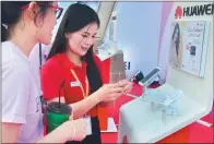  ?? XINHUA ?? A representa­tive of Huawei Technologi­es introduces a new smartphone to a visitor in Vientiane, Laos. The Shenzhenhe­adquartere­d company ranked top of the internatio­nal patent filer chart by corporatio­n in 2015.