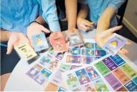  ?? Photo / Warren Buckland ?? In their hands are prototypes while designs on the table made by an English freelancer are close to the final cards, which will be printed by Mammoth Design in Onekawa.