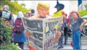  ?? REUTERS ?? A man in a Trump mask pretends to read a fake newspaper.
