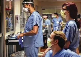  ??  ?? Dr. Javed Jeffrey, left, ECMO Specialist Shelby Wingfield, right, and Clayton Lundgren, center, observe a patient before visiting with him in the ECMO unit at Methodist Hospital.