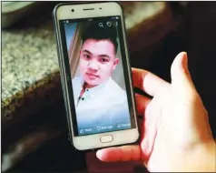  ?? The Associated Press ?? IMAGE OF MISSING SON: In this Oct. 28 photo, Hoang Thi Ai, mother of Hoang Van Tiep, who is feared to be among the England truck dead, hold a phone showing a photo of Tiep in Dien Thinh village, Nghe An province, Vietnam. Tiep, who had been in France, told his parents his prospects in France were poor, and he wanted to go to England for a better-paying job working at nail salons. “Nail bars,” as they are known in Britain, are go-to employment spots for Asian migrants but often pay barely enough to scrape by. He asked for his parents’ financial help, saying the move would help pay off the debt.