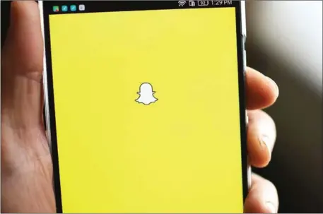  ?? ROBYN BECK/AFP ?? The Snapchat logo is displayed on a mobile phone. After a dearth of technology listings in 2016, Snapchat parent Snap priced its initial public offering at $17 a share on Wednesday.