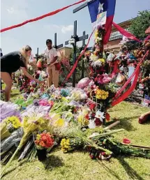  ?? Associated Press ?? Visitors to a makeshift memorial leave flowers in front of a large cross at the mall where several people were killed in Allen, Texas.