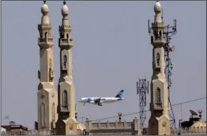  ?? The Associated Press ?? HEIGHTENED SECURITY: An EgyptAir plane flies past minarets of a mosque as it approaches Cairo Internatio­nal Airport on May 21, 2016, in Cairo, Egypt.