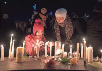  ?? DARREN CALABRESE, THE CANADIAN PRESS, VIA AP ?? Sawsan Idris, right, lights candles Monday with her daughters Lara and Tamara while attending a vigil in Moncton, New Brunswick, for victims of the shooting at a Quebec City mosque.