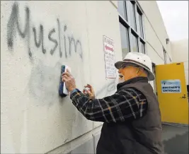  ?? Rich Pedroncell­i ?? The Associated Press Tom Garing cleans up racist graffiti painted on the side of a mosque in what officials are calling an apparent hate crime in Roseville, Calif. California’s attorney general says the number of hate crimes increased about 11 percent...