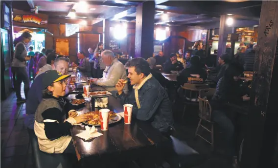  ?? Photos by Paul Chinn / The Chronicle ?? Colton (left) and Kobe Carr have a pizza with their father, Gavin Carr, at the Oasis. Regulars and old-timers are flocking to dine and drink there for the last time.
