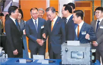  ?? Yonhap ?? President Moon Jae-in talks to Hyundai Motor Group Executive Vice Chairman Chung Eui-sun, second from left in the front row, while looking at the fuel cell systems displayed at Ulsan City Hall, Thursday. Left is Minister of Trade, Industry and Energy Sung Yun-mo.