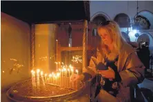  ?? MAJDI MOHAMMED/ASSOCIATED PRESS ?? A visitor lights a candle Tuesday at the Church of the Nativity, built on top of the site where Christians believe Jesus Christ was born on Christmas Eve in the West Bank city of Bethlehem.