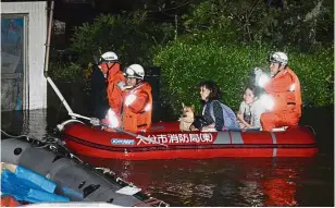  ??  ?? In safe hands: Rescuers evacuating local residents from an inundated house due to heavy rain triggered by Talim, in Oita, southern Japan. — Reuters