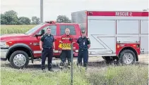  ?? WAINFLEET FIRE AND EMERGENCY SERVICES ?? Wainfleet Fire and Emergency Services Deputy Chief Shawn Schutten, left, and Chief Morgan Alcock flank farmer and volunteer firefighte­r Ted Hessels in front of a yellow sign marking a farm field in Wainfleet.