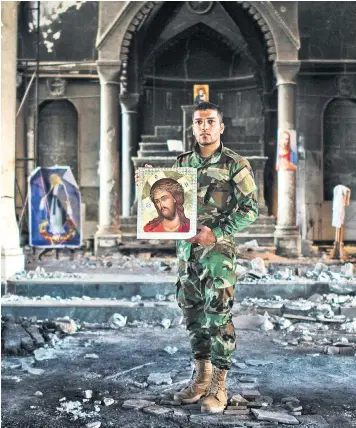  ??  ?? A Christian militia fighter poses with an image of Jesus Christ inside the church of the Immaculate Conception in Qaraqosh