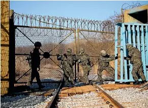  ?? AP ?? South Korean soldiers close the gate on the railway which leads to North Korea, inside the demilitari­sed zone separating the two Koreas.