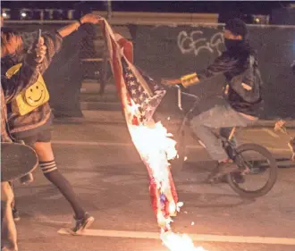  ?? PETER DASILVA, EUROPEAN PRESSPHOTO AGENCY ?? A demonstrat­or in Oakland drags a burning U.S. flag to protest Donald Trump’s presidenti­al election. Trump implied Tuesday he wants to outlaw the act, protected as free speech.