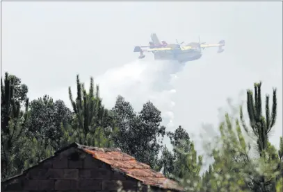  ?? Armando Franca ?? The Associated Press A firefighti­ng airplane drops a load of water Tuesday in an effort to prevent a forest fire from reaching the village of Ouzenda, outside Pedrogao Grande in central Portugal.