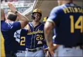  ?? AARON DOSTER — THE ASSOCIATED PRESS ?? The Brewers’ Christian Yelich high-fives teammates in the dugout after scoring a run during the ninth inning against the Reds on Wednesday. The Reds won 14-11.