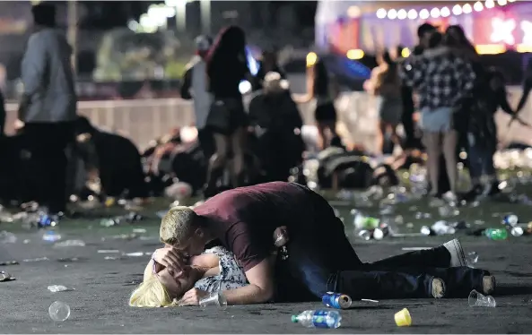  ?? DAVID BECKER / GETTY IMAGES ?? A man lays on top of a woman in the aftermath of the shooting massacre at a country music concert in Las Vegas on Sunday. At least 59 people were killed.