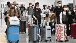  ?? HYOSUB SHIN / HYOSUB.SHIN@AJC.COM ?? Internatio­nal travelers taking coronaviru­s precaution­s arrive Tuesday at Hartsfield-Jackson Internatio­nal Airport. The coronaviru­s fallout represents a sudden reckoning for the American airline industry after years of economic growth spurred rising traffic and profits.