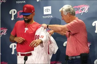  ?? LYNNE SLADKY — THE ASSOCIATED PRESS ?? New Phillie Nick Castellano­s, left, is helped in putting on his ceremonial jersey by President of Baseball Operations Dave Dombrowski at an introducto­ry press conference Wednesday. Dombrowski, who drafted Castellano­s with the Tigers in 2010, splashed out $100 million for a player he hopes will tip the Phillies over into being winners, on and off the field.