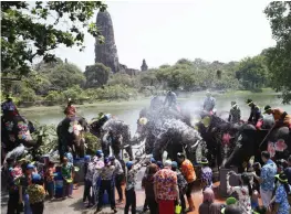  ?? — AP ?? Tourists splash water to elephants ahead of the Buddhist New Year, known as Songkran, in Ayutthaya province, central Thailand on Wednesday.