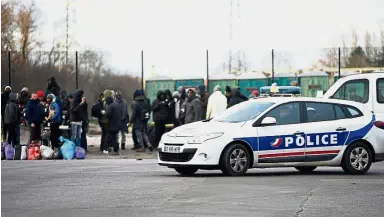  ?? — AFP ?? Heightened security: Police keeping watch near a crowd in Calais following the brawl.