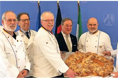  ?? FOTO: KOSCHE ?? Jörg von Polheim (3. v. l.), Landesinnu­ngsmeister des Bäckerhand­swerks, und Kollegen übergaben Ministerpr­äsident Armin Laschet (2. v. r.) eine große Brezel.