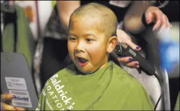  ??  ?? Tayden Nguyen, 7, reacts to seeing his shaved head for the first time Saturday at Shave for the Cure at McMullan’s Irish Pub.