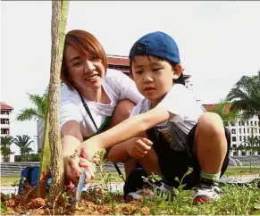  ??  ?? Teaching the young: Wong Qi Hui, six, and his mother Wendy Lee, 41, planting a tree at the Eco-green awareness campaign at Xiamen University Malaysia campus in Sepang, Selangor.