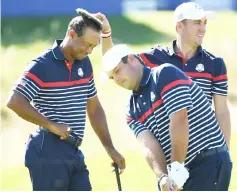  ?? — AFP photo ?? Woods (left) smiles with a tuft of grass on his head placed there by Justin Thomas (right) as Patrick Reed (centre) plays a shot during a practice session ahead of the 42nd Ryder Cup at Le Golf National Course at Saint-Quentin-en-Yvelines, south-west of Paris.