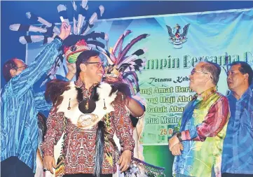  ??  ?? Temenggong Wilfred Billy Panyau (left) places the headgear on Abang Johari as (from right) Ugak and Uggah look on.