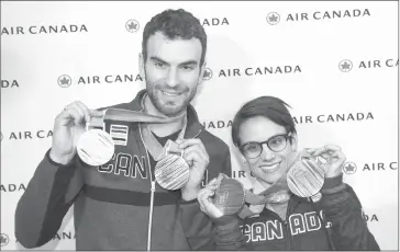  ?? THE CANADIAN PRESS/GRAHAM HUGHE ?? Figure skaters Meagan Duhamel and Eric Radford show their Pyeongchan­g 2018 Olympic Winter medals on their arrival back from the games at Trudeau airport in Montreal, Monday, February 26, 2018. Duhamel and Radford, who teamed up for two pairs world...