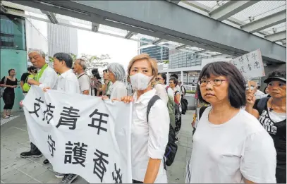  ?? The Associated Press ?? Actress and singer Deanie Ip, center, wears a mask as she holds a banner in support of young people during a march Wednesday in Hong Kong. She said police shouldn’t use heavy-handed tactics against protesters who “have no guns.”