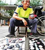  ??  ?? This photo shows artist Wu Rong-bi, also as known as “Uncle Stone”, displaying colourfull­y painted stones along a street in Taipei.—AFP photos