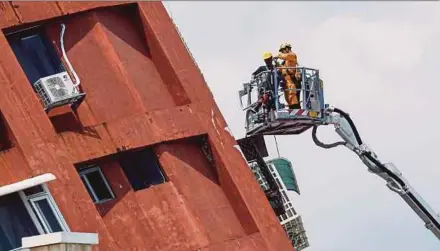 ?? REUTERS PIc ?? Workers carrying out operations while on an elevated platform of a firefighti­ng truck at the site where a building collapsed due to an earthquake in Hualien, Taiwan, yesterday.