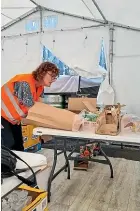  ?? ?? Lynn Gill, who took leave without pay from her full-time job in Palmerston North to go to Ukraine for humanitari­an work, makes a packet of goods for people affected in the war-hit country.