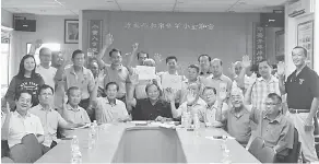  ??  ?? KAMI BANTAH: Tang (duduk, tengah) bersama mereka yang hadir pada mesyuarat memberikan isyarat membantah pelaksanaa­n seni khat dan tulisan Jawi pada tahun depan.